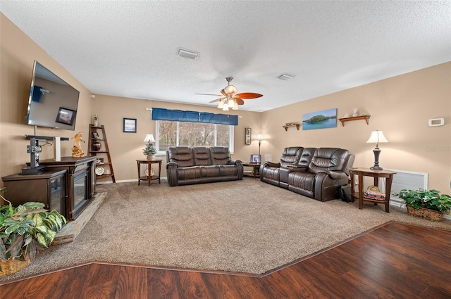 carpeted living room with ceiling fan and a textured ceiling