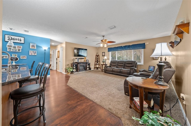 living room featuring ceiling fan, wood-type flooring, and a textured ceiling