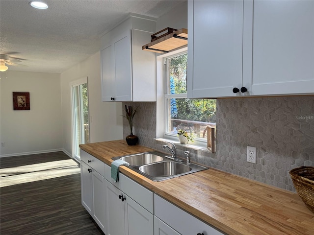 kitchen featuring decorative backsplash, ceiling fan, sink, butcher block countertops, and white cabinetry