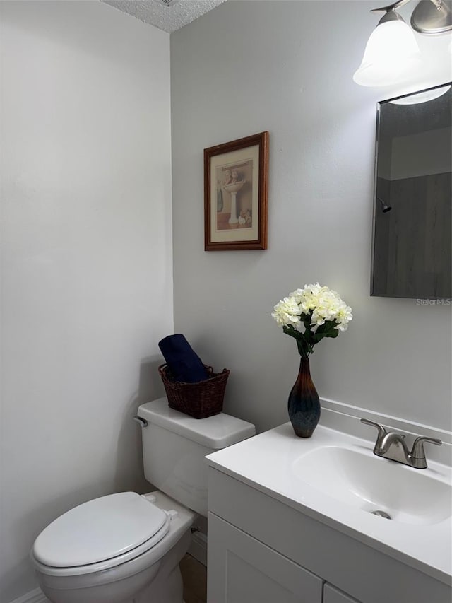 bathroom with a textured ceiling, vanity, and toilet