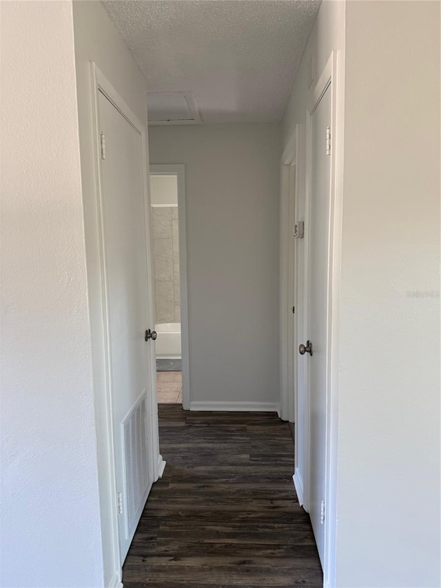 hallway featuring dark hardwood / wood-style flooring and a textured ceiling