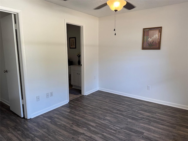 spare room featuring ceiling fan, dark wood-type flooring, and a textured ceiling