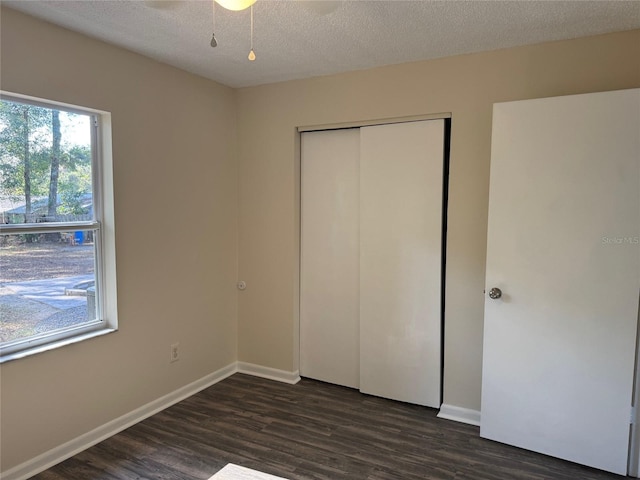 unfurnished bedroom with dark hardwood / wood-style flooring, a textured ceiling, and a closet