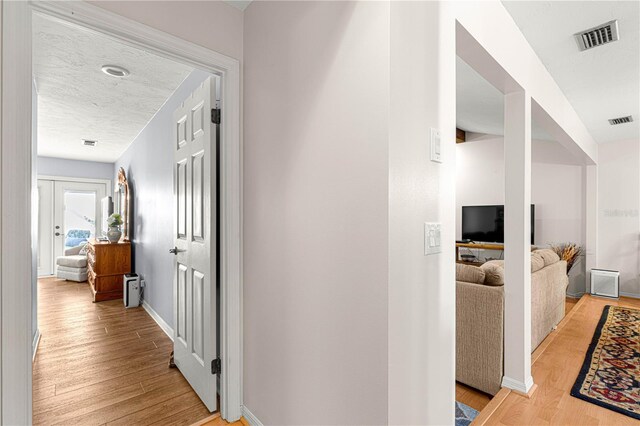 hallway with french doors and light hardwood / wood-style floors