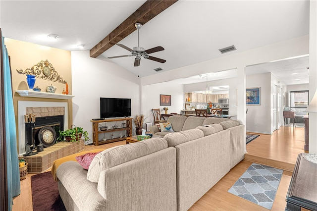 living room featuring vaulted ceiling with beams, light wood-type flooring, and ceiling fan