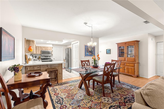 dining space featuring light hardwood / wood-style floors and a notable chandelier