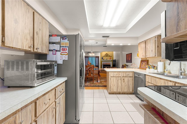 kitchen featuring kitchen peninsula, appliances with stainless steel finishes, a tray ceiling, pendant lighting, and light tile patterned flooring