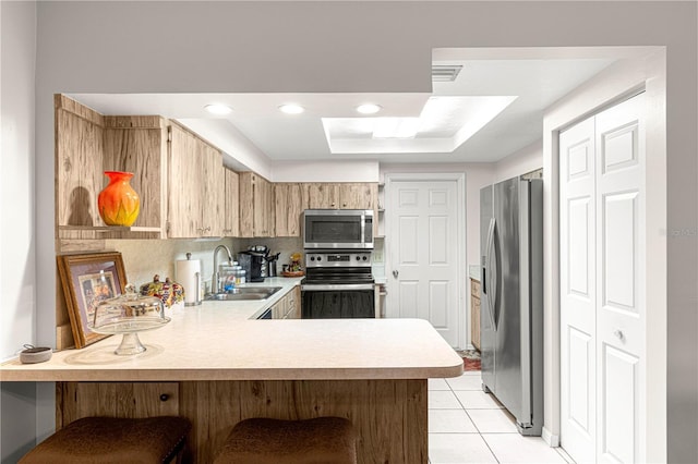 kitchen with sink, stainless steel appliances, kitchen peninsula, a breakfast bar, and light tile patterned flooring