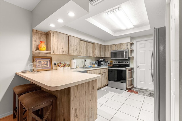 kitchen featuring kitchen peninsula, a kitchen breakfast bar, stainless steel appliances, sink, and light tile patterned flooring