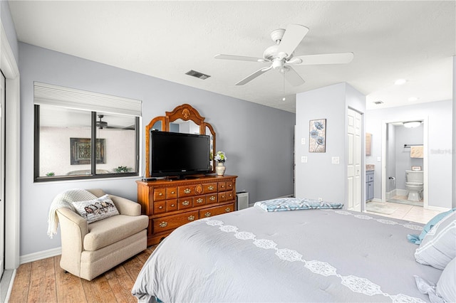 bedroom with ensuite bathroom, a textured ceiling, ceiling fan, light hardwood / wood-style flooring, and a closet