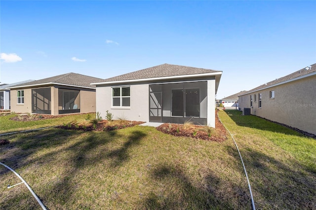 rear view of property featuring a lawn, central AC, and a sunroom