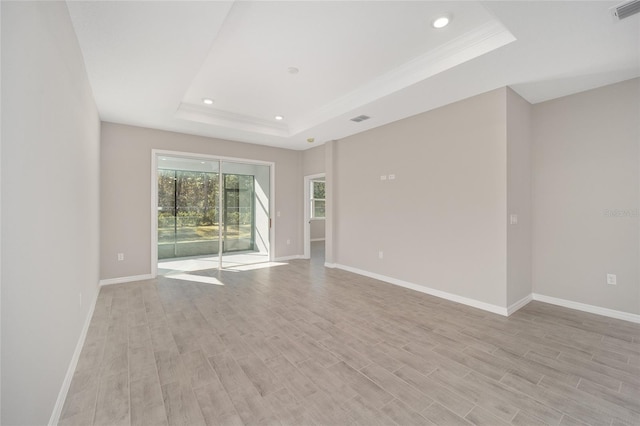 spare room with light hardwood / wood-style flooring and a raised ceiling