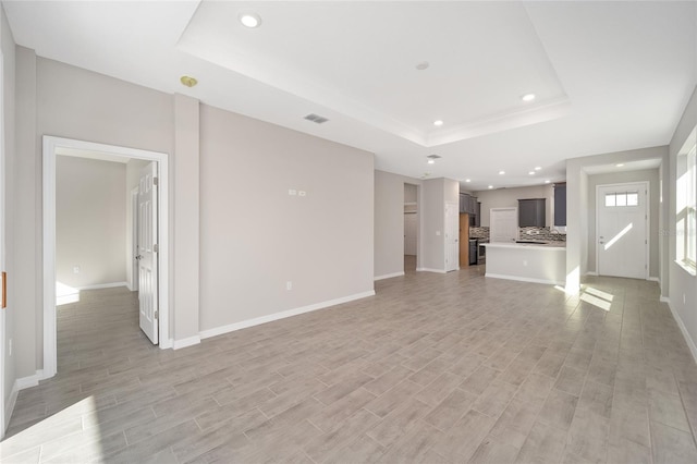 unfurnished living room featuring light hardwood / wood-style flooring and a raised ceiling