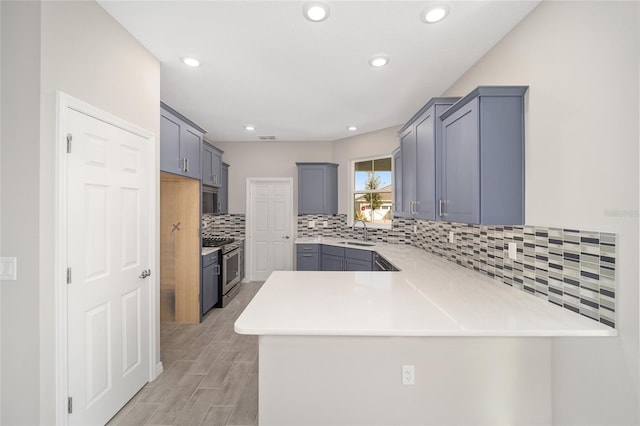 kitchen featuring backsplash, kitchen peninsula, stainless steel range, and sink