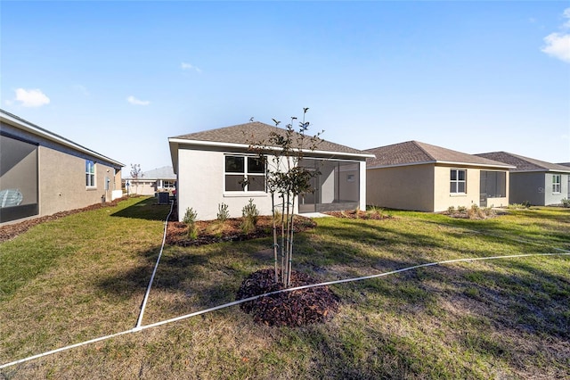 back of property with a lawn and a sunroom