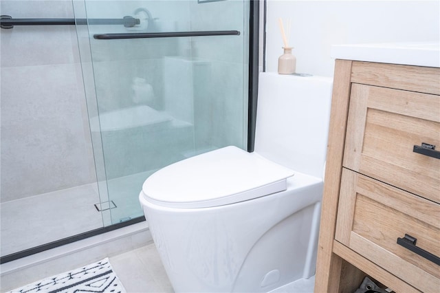 bathroom with tile patterned floors, vanity, toilet, and a shower with shower door