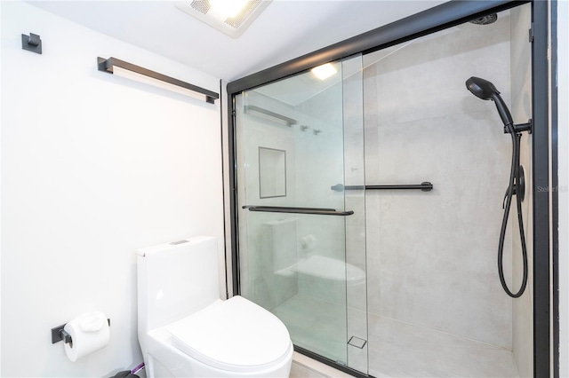 bathroom featuring a shower with shower door and toilet