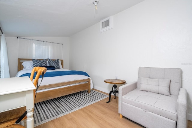 bedroom with light wood-type flooring and vaulted ceiling