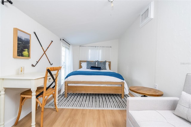 bedroom featuring light wood-type flooring and vaulted ceiling