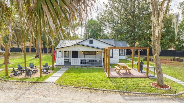 view of front of home with covered porch, a fire pit, a patio area, and a front yard