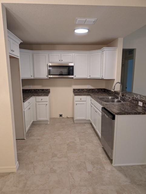 kitchen with dark stone countertops, sink, white cabinets, and appliances with stainless steel finishes