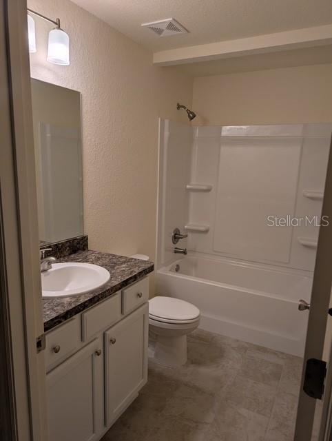 full bathroom with vanity, a textured ceiling, toilet, and  shower combination