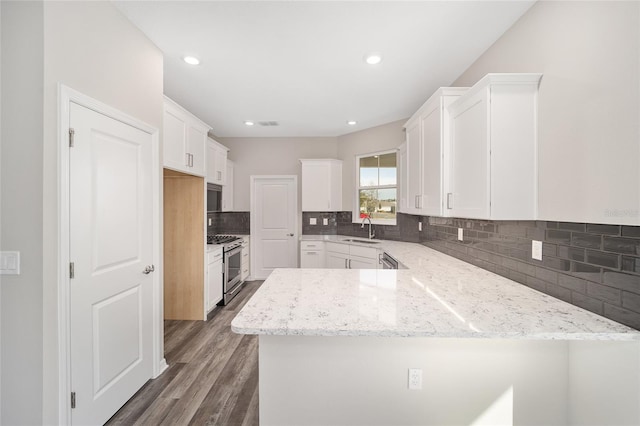 kitchen featuring kitchen peninsula, light stone counters, stainless steel appliances, sink, and white cabinetry