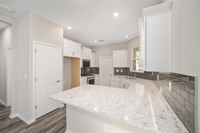 kitchen with kitchen peninsula, sink, white cabinets, and appliances with stainless steel finishes