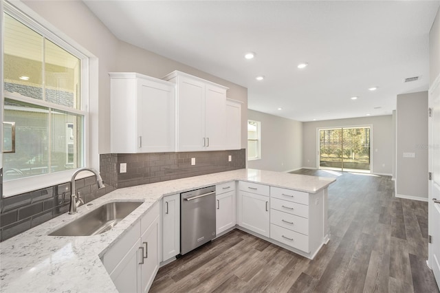 kitchen with kitchen peninsula, light stone counters, sink, dishwasher, and white cabinetry