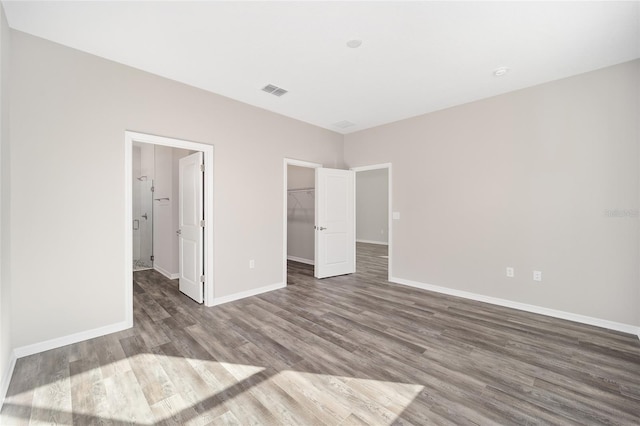 unfurnished bedroom with wood-type flooring, a spacious closet, and a closet