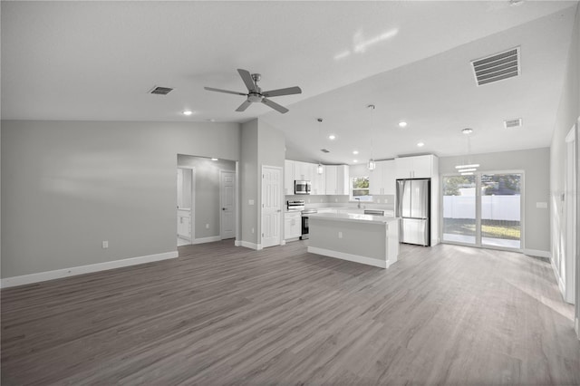 kitchen with appliances with stainless steel finishes, ceiling fan, decorative light fixtures, white cabinets, and a center island