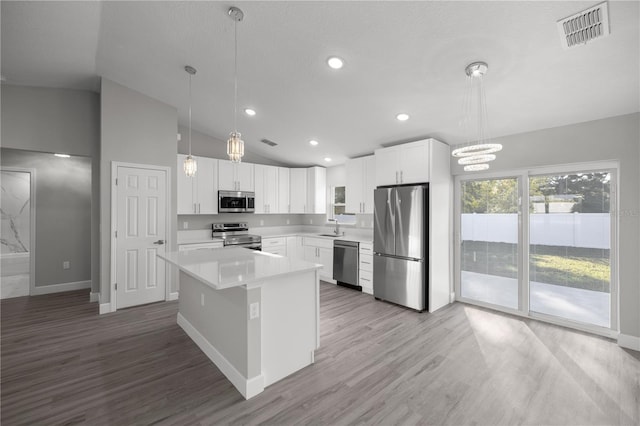 kitchen with white cabinetry, sink, hanging light fixtures, stainless steel appliances, and a kitchen island