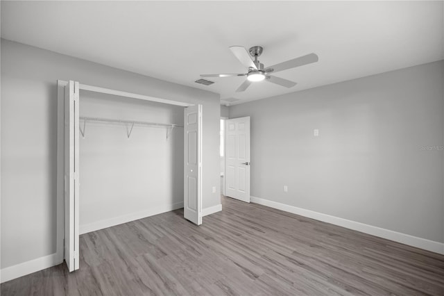 unfurnished bedroom with ceiling fan, a closet, and hardwood / wood-style flooring