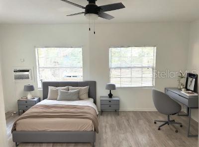 bedroom featuring a wall unit AC, light hardwood / wood-style floors, and ceiling fan