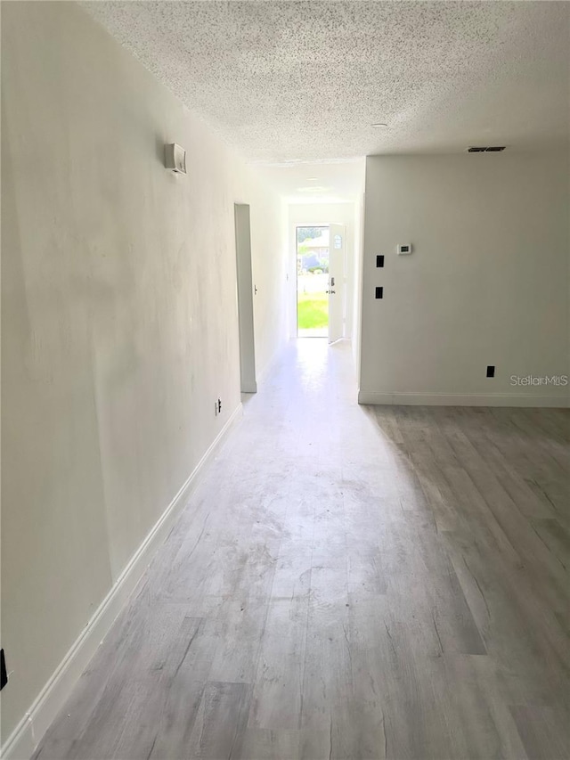 hall featuring light hardwood / wood-style floors and a textured ceiling