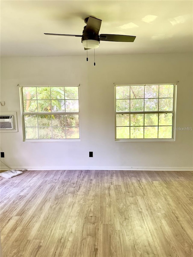 spare room with ceiling fan, a wall mounted AC, and light hardwood / wood-style flooring