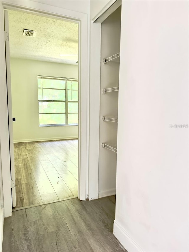 corridor with wood-type flooring and a textured ceiling