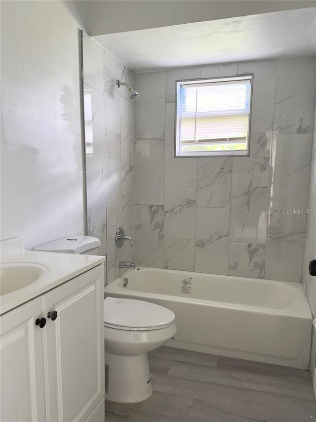 full bathroom with tiled shower / bath combo, vanity, wood-type flooring, and toilet