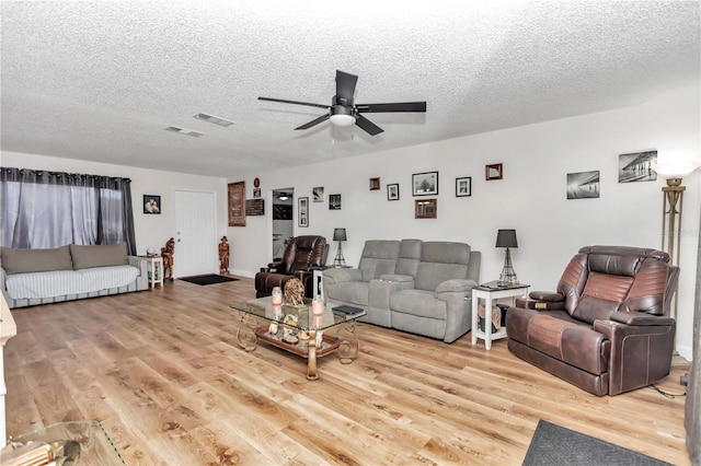 living room with a textured ceiling, ceiling fan, and light hardwood / wood-style floors