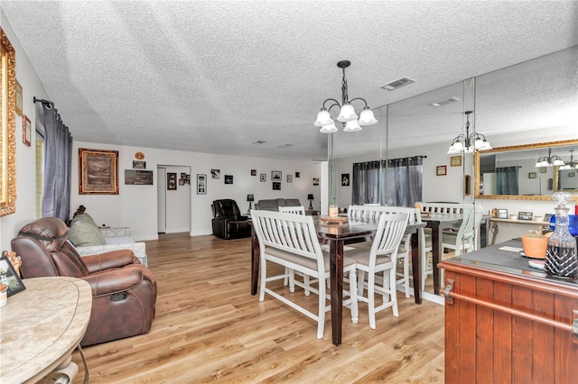 dining room featuring a notable chandelier, a textured ceiling, and light hardwood / wood-style floors