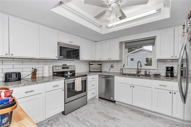 kitchen featuring sink, white cabinets, a tray ceiling, and stainless steel appliances