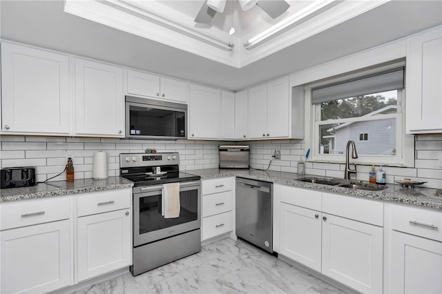 kitchen featuring appliances with stainless steel finishes, a raised ceiling, crown molding, white cabinets, and sink