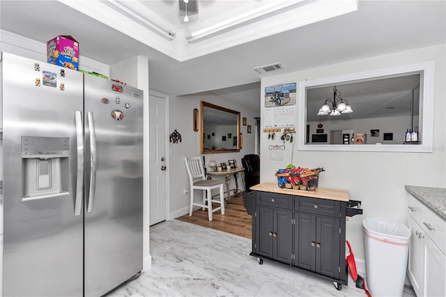 kitchen featuring decorative light fixtures, wooden counters, a notable chandelier, white cabinetry, and stainless steel fridge