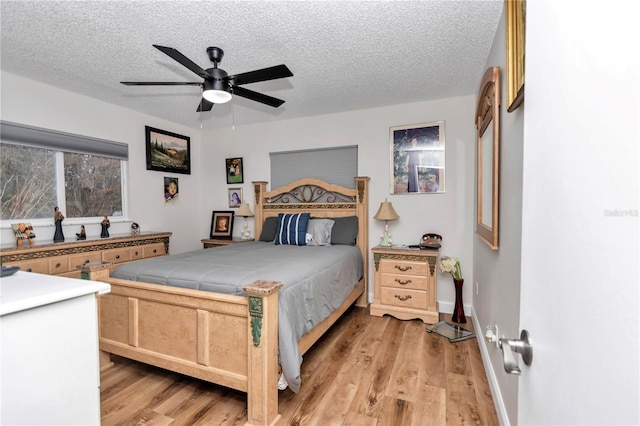 bedroom featuring ceiling fan, light hardwood / wood-style floors, and a textured ceiling