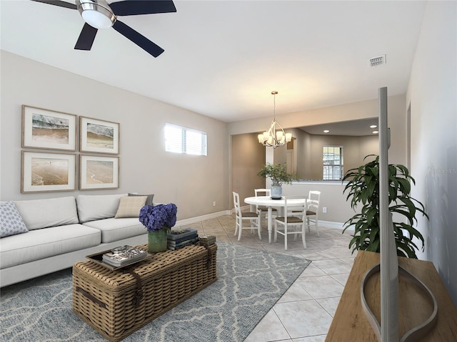 living room featuring plenty of natural light, light tile patterned flooring, and ceiling fan with notable chandelier