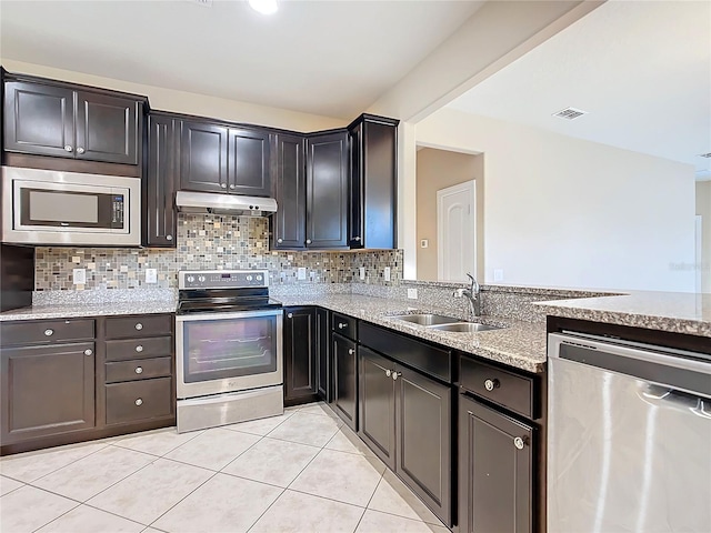 kitchen featuring sink, stainless steel appliances, tasteful backsplash, light stone counters, and light tile patterned floors