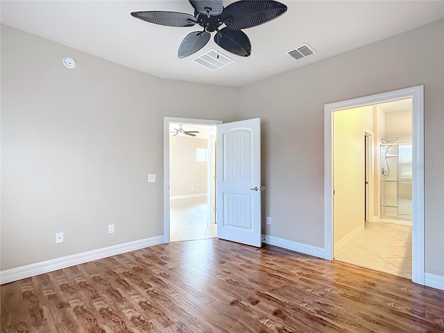 unfurnished bedroom with ensuite bath, ceiling fan, and hardwood / wood-style floors