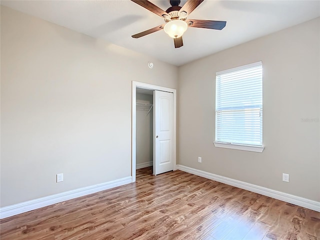 unfurnished bedroom featuring ceiling fan, light hardwood / wood-style floors, and a closet