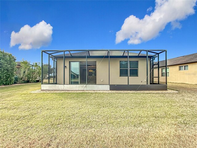 back of property with a lawn and glass enclosure