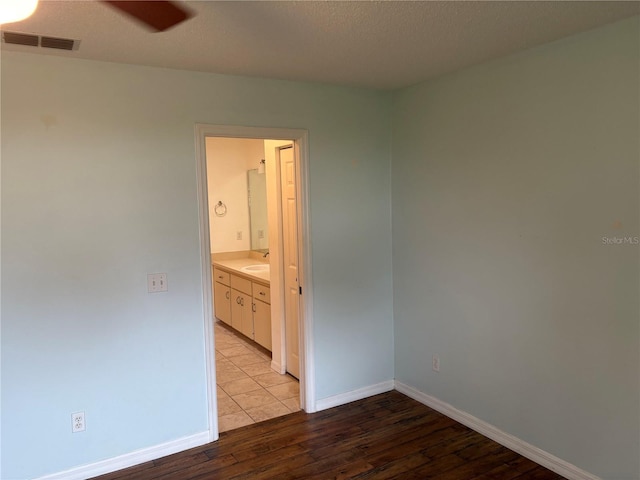 empty room featuring a textured ceiling, light wood-type flooring, and ceiling fan